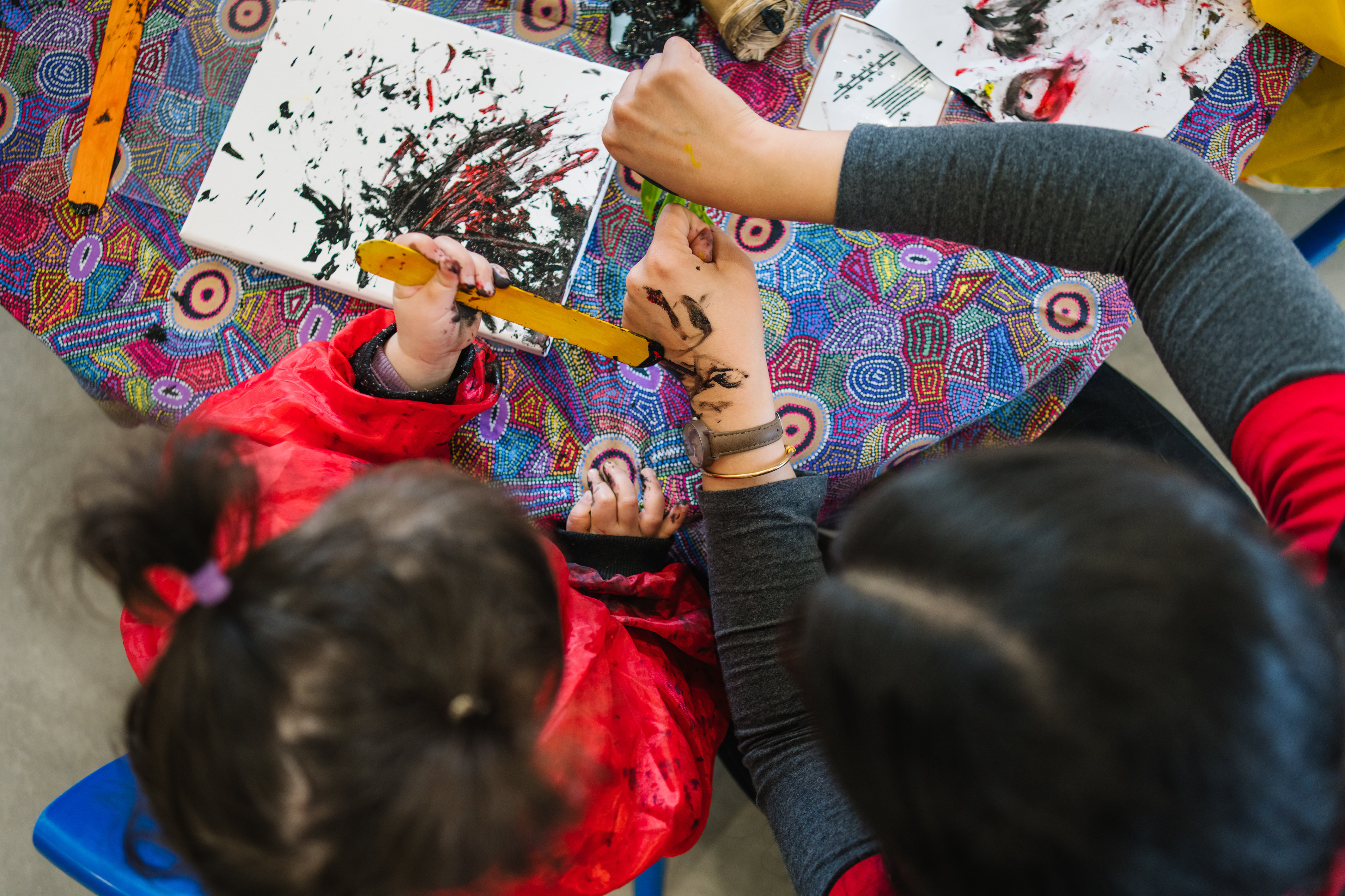 child and educator engaged in painting